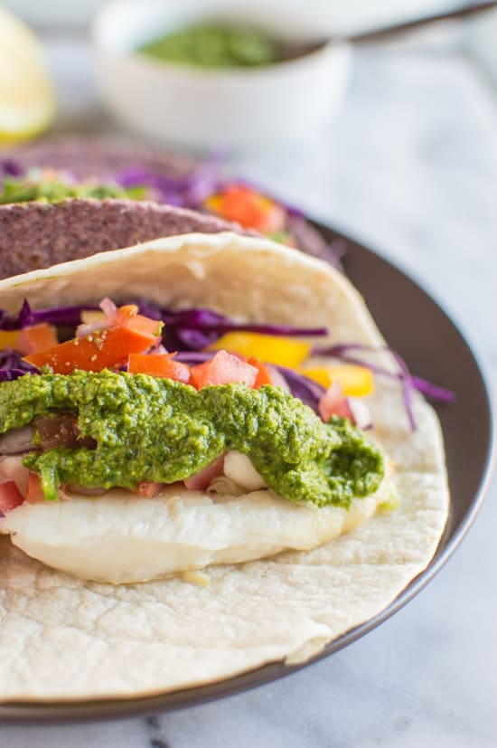 Delicious fish tacos with a spicy and tangy green harissa. Add some spice to your dinner or lunch with these healthy tacos! | healthynibblesandbits.com