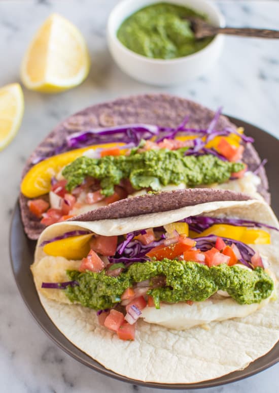 Delicious fish tacos with a spicy and tangy green harissa. Add some spice to your dinner or lunch with these healthy tacos! | healthynibblesandbits.com