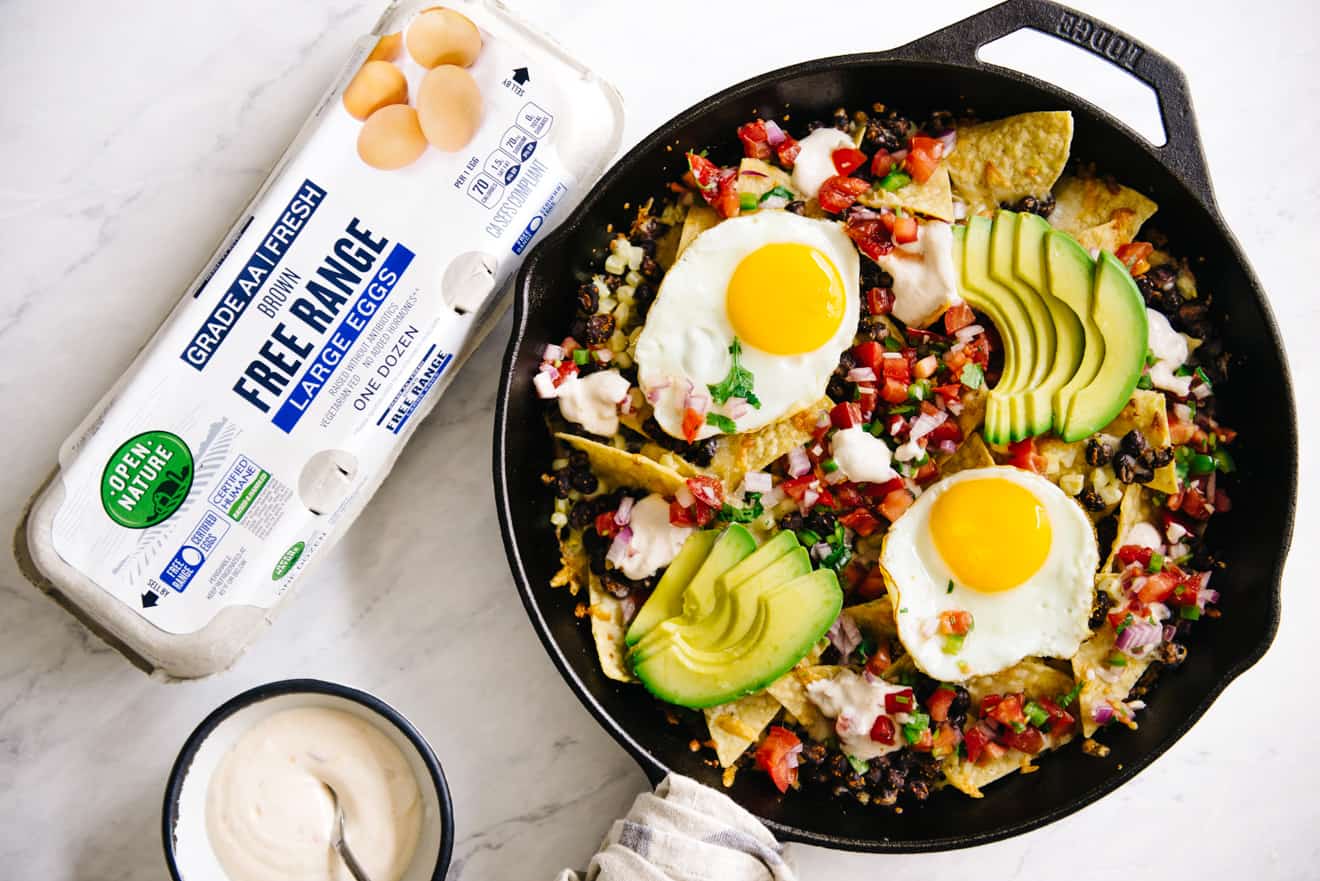 nachos in cast iron pan with a carton of eggs to the left