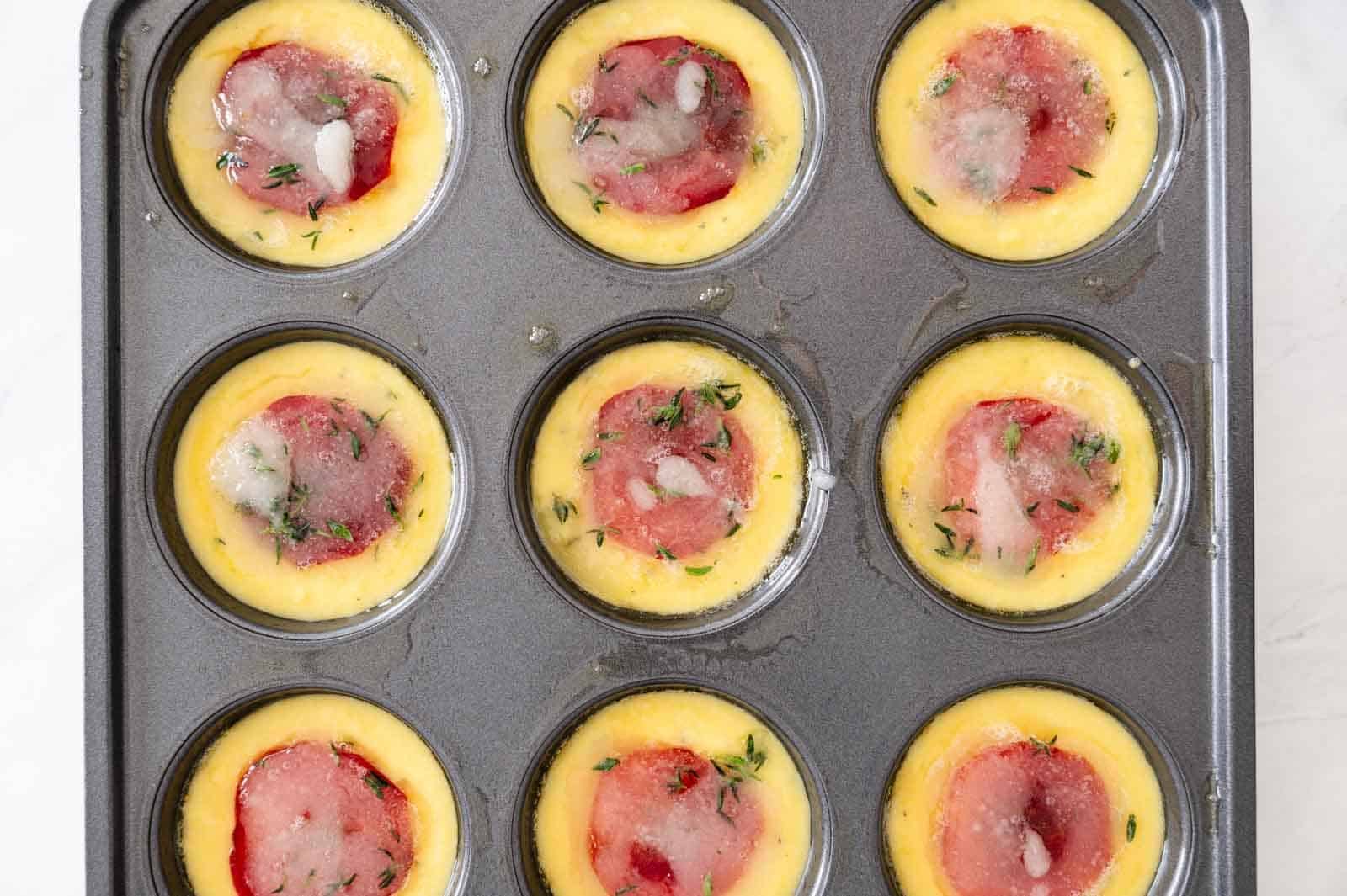 Corn batter in muffin pan with plums and sugar topping